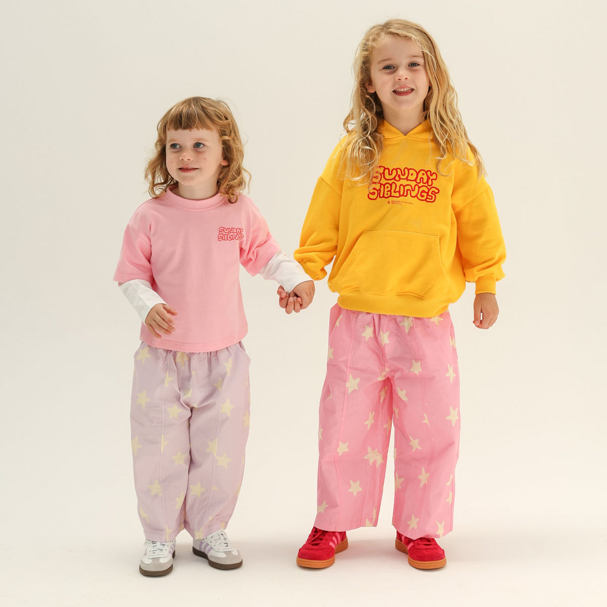 Two children wearing colorful outfits on a plain background